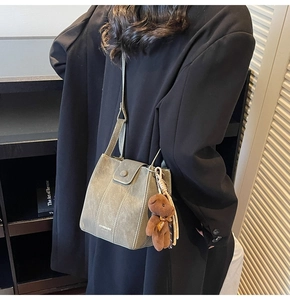 Détail d'un sac seau vert avec pendentif ours porté sur un manteau en laine noir