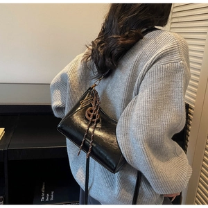 Vista posteriore dettagliata della borsa sottobraccio nera lucida con anello e corda su modella