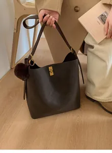 Vue détaillée du sac seau marron mat avec pompon en fourrure et boucle métallique