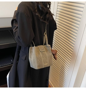 Détail du sac seau vert gris avec surpiqûres blanches et pendentif ours en peluche
