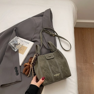 Détail du sac seau en daim vert foncé avec surpiqûres blanches et pendentif ours mignon