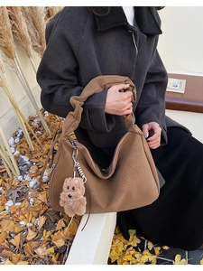 Brown frosted leather hobo bag with pleated handle and cute bear charm in autumn setting