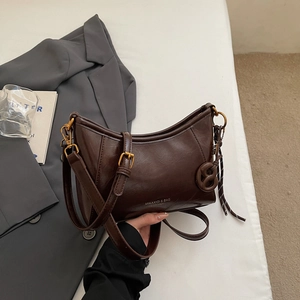 Dettaglio della borsa sottobraccio in pelle marrone lucida con fibbia dorata e tracolla