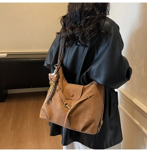 Close-up of caramel faux leather tote bag with plush bear charm and textured finish