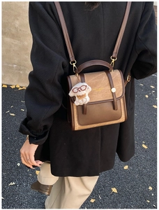 Détail d'un sac à dos rétro en daim bicolore avec un charmant pendentif chien blanc