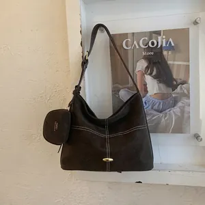 Detail view of large dark brown tote bag with contrast stitching and mini coin purse charm