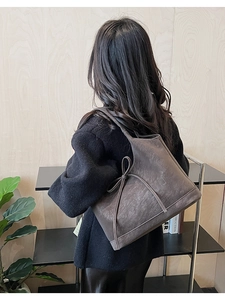Detailed view of dark brown leather tote bag with side bow and embossed HU logo