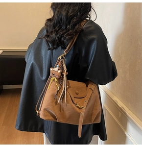 Detail of vintage brown tote bag with bear charm and tassel on adjustable strap