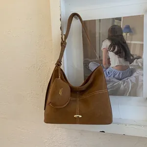 Detail view of brown matte leather tote bag with white contrast stitching and mini pouch