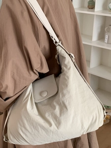 Minimalist cream tote bag with adjustable strap and front pocket worn for daily commute