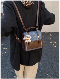 Détail d'un sac à dos rétro en daim bicolore avec un pendentif chien en peluche
