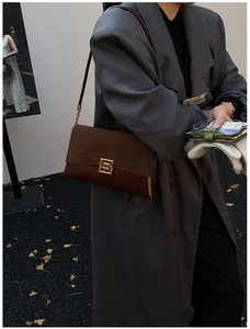 Détail d'un sac bandoulière vintage en daim marron avec boucle métallique dorée chic