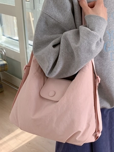 Pink large capacity nylon tote bag for women shown as a stylish crossbody on a model