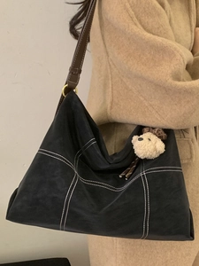 Minimalist black suede tote bag with white contrast stitching and bear charm