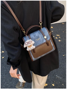 Vue détaillée d'un sac à dos patchwork en denim bleu et cuir marron avec un charme de chien