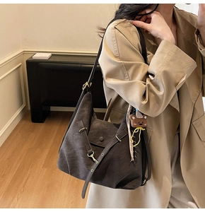 Detail view of a large dark brown retro tote bag with adjustable straps and bear pendant