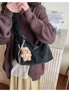 Detail of black cloud bag with pleated strap and a cute brown plush bear charm