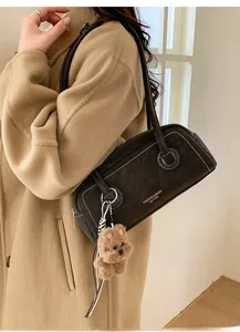Detail of vintage dark brown faux leather shoulder bag with white stitching and plush charm