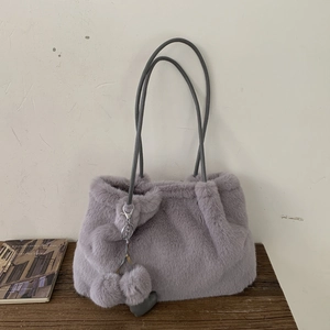 Dettaglio della borsa a secchiello viola in peluche con ciondolo a cuore e pelliccia