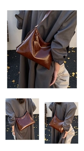 Detail of dark brown glossy leather tote bag with adjustable strap in a street style setting
