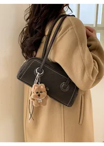 Detail of black suede shoulder bag with contrast stitching and brown dog charm accessory