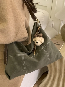 Quilted green leather hobo bag with plush dog charm shown on a female model shoulder