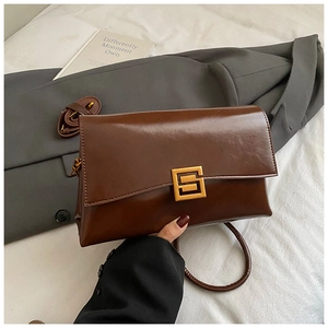 Détail d'un sac à main en cuir marron avec un fermoir métallique doré en forme de S