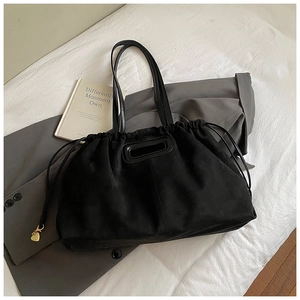 Détail du sac cabas en suède noir avec fermeture à cordon et breloque coeur dorée