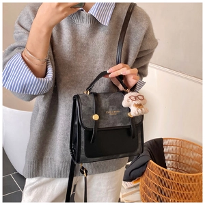 Détail d'un sac à dos en daim color-block avec boucle dorée et breloque chiot en peluche