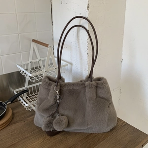 Dettaglio della borsa a secchiello in ecopelliccia marrone scuro con eleganti manici sottili