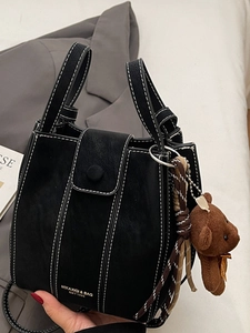 Sac seau noir minimaliste avec surpiqûres blanches contrastées et porte-clés ours
