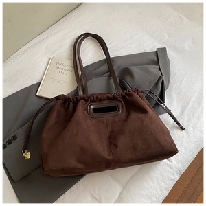 Détail du sac cabas en daim avec fermeture à cordon et pendentif en cœur doré
