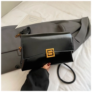 Détail d'un sac bandoulière noir brillant avec un fermoir géométrique doré élégant