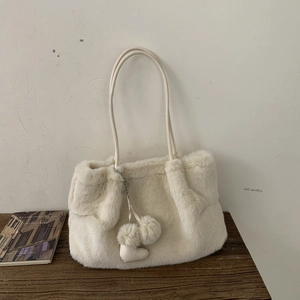 Dettaglio della borsa a secchiello in peluche bianco con trama soffice e ciondolo a cuore