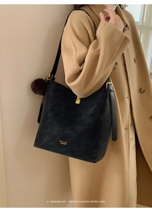 Détail du sac seau noir vintage avec fermoir doré et breloque en fourrure marron