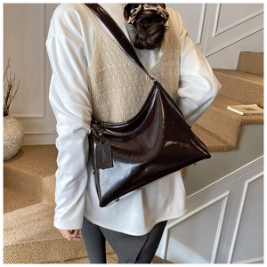 Detailed view of the glossy dark brown patent leather texture and side brand tag on tote
