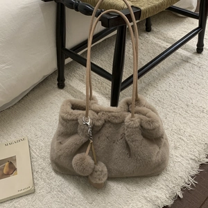 Secchiello accogliente in ecopelliccia albicocca con ciondolo peluche su una sedia