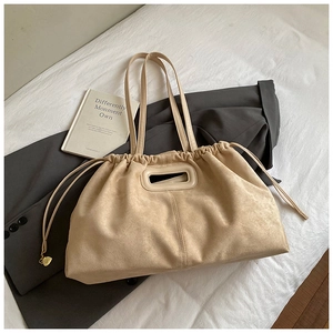 Détail du sac cabas en daim beige montrant le cordon de serrage et le charme cœur