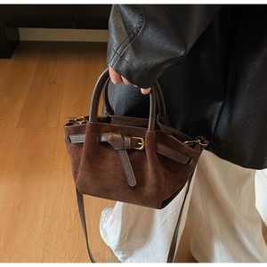 Dettaglio della borsa in pelle scamosciata marrone con manici in pelle e finiture dorate