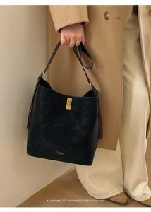 Détail du sac seau en cuir noir avec fermoir tournant doré et texture de grain fin