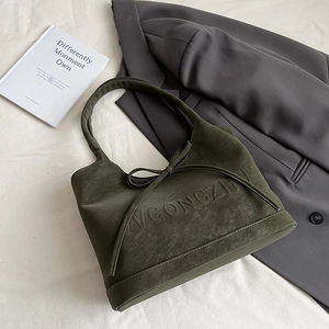 Detailansicht der grünen Wildledertasche mit dekorativer Schleife und Prägebuchstaben