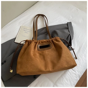 Vue détaillée du sac cabas en daim marron avec cordon de serrage et breloque coeur dorée