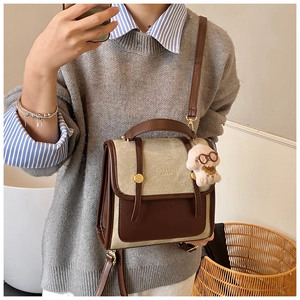 Détail d'un sac à dos rétro en daim bicolore avec boucles dorées et breloque peluche
