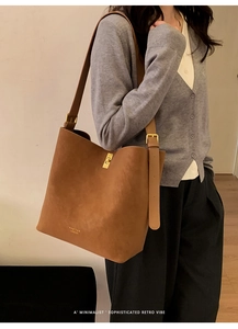 Détail d'un sac seau en cuir marron avec garnitures dorées et logo de la marque sur le côté