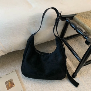 Gros plan détaillé d'un sac hobo en daim noir avec bandoulière réglable sur une parure blanche