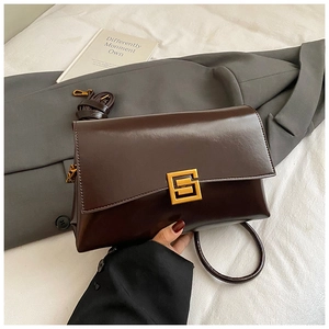Détail d'un sac bandoulière en similicuir marron foncé brillant avec fermoir doré