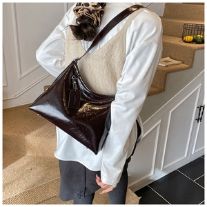Detail of deep brown glossy leather tote bag showing smooth texture and spacious design