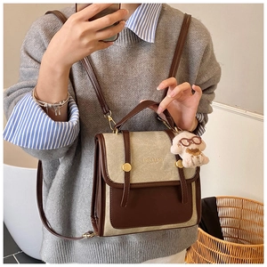 Détail d'un sac à dos vintage bicolore avec boucles dorées et un charmant petit chien