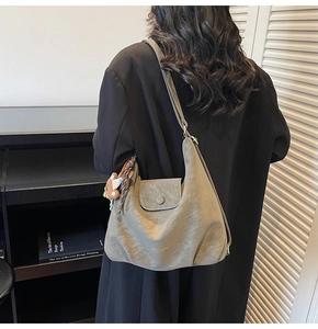 Detailansicht der großen olivgrünen Hobo-Tasche mit Bärenanhänger und goldener Aufschrift