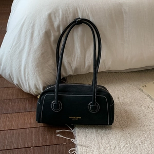 Close-up of vintage black suede handbag with white contrast stitching and gold text detail